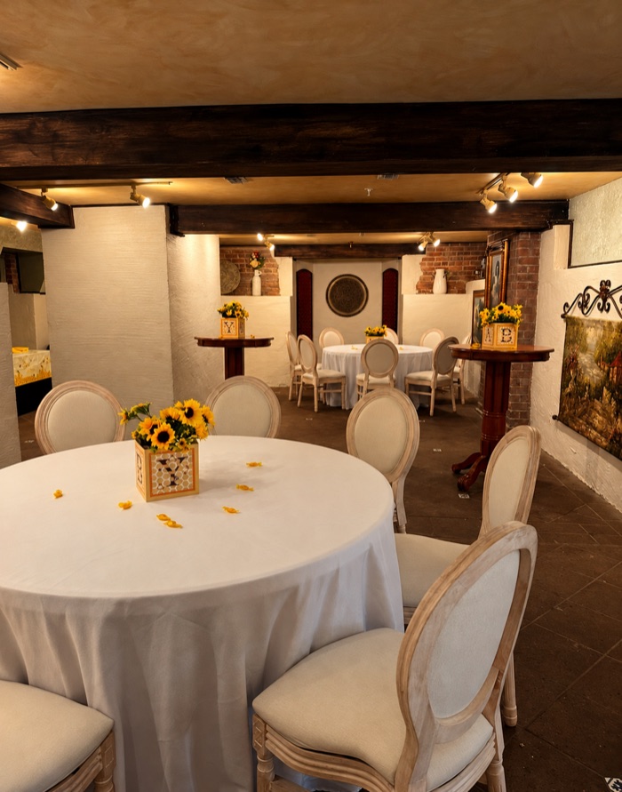 Round dining tables with white linens and sunflower centerpieces in the Cellars