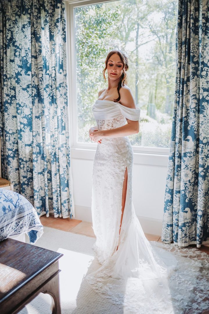 Brooke standing by the window in her wedding dress