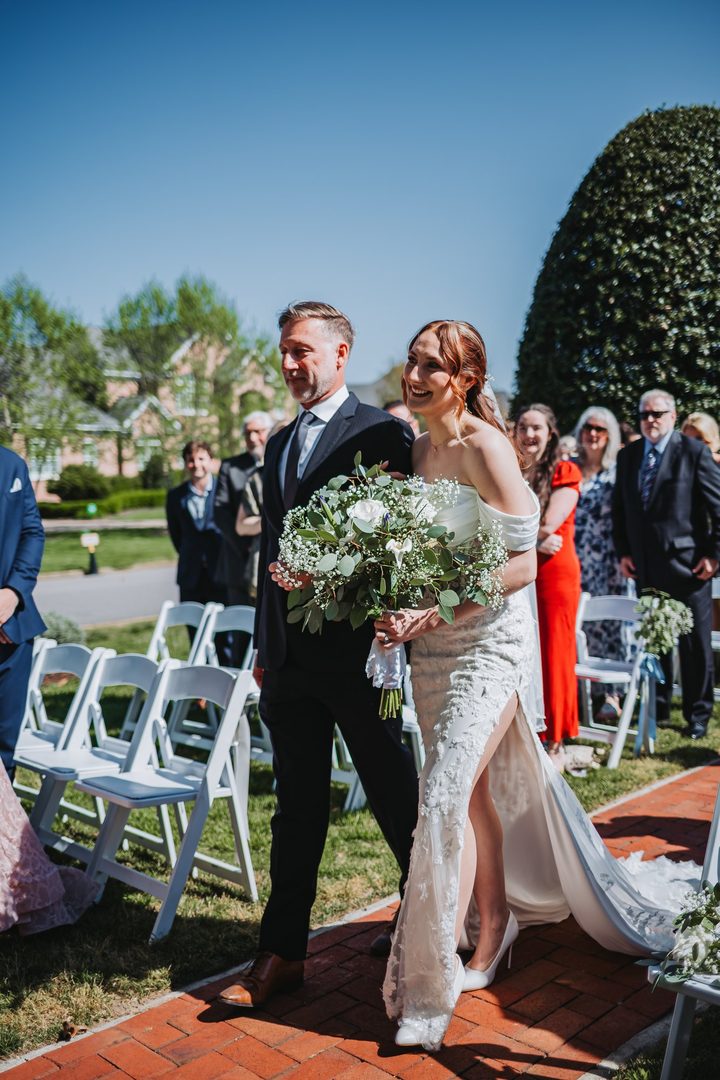 Brooke walking down the brick garden aisle with her escort