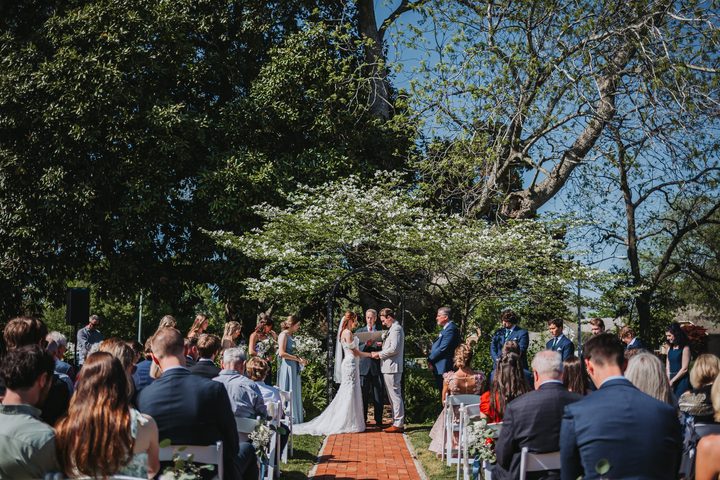 Brooke and Max at the altar beneath the garden trees