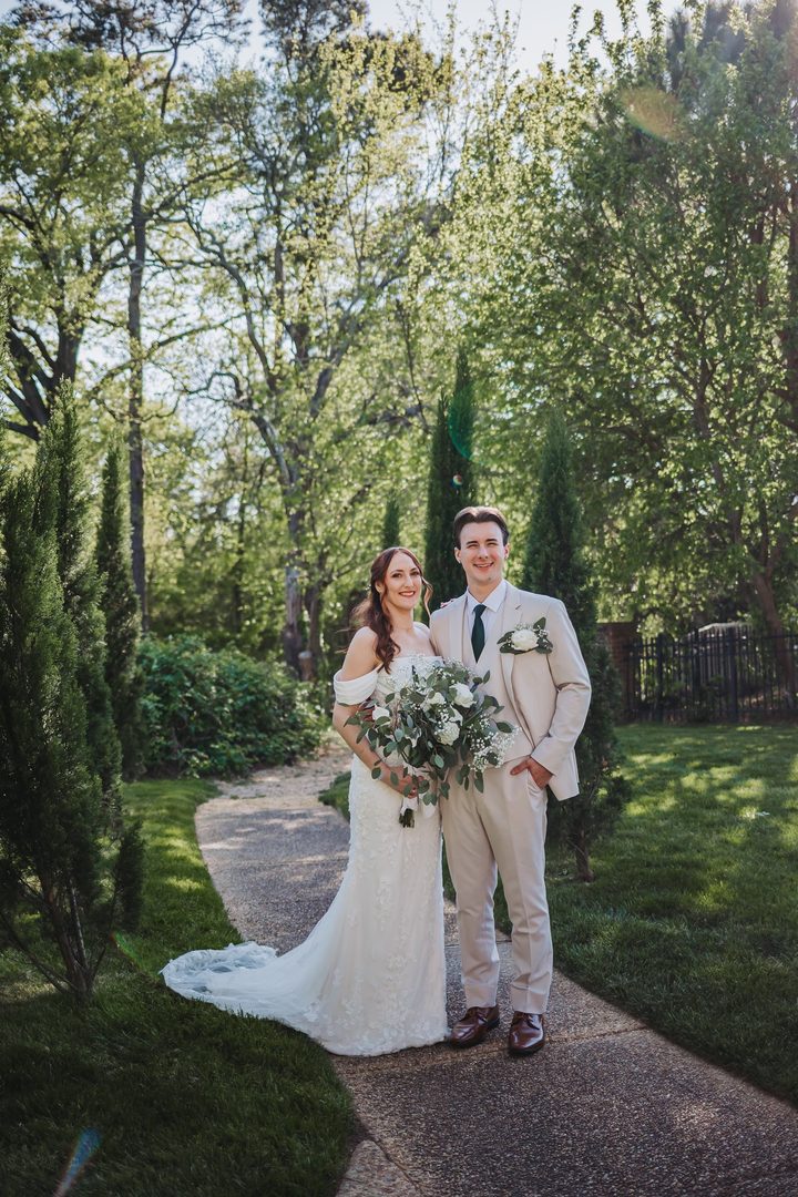 Brooke and Max smiling beneath the spring trees