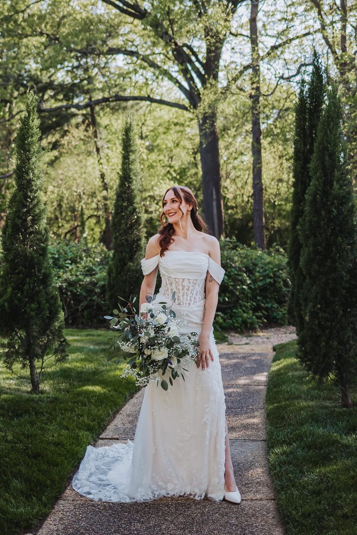 Brooke with her bouquet and wedding dress on the garden path