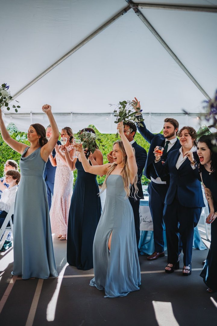 The wedding party cheering beneath the reception tent