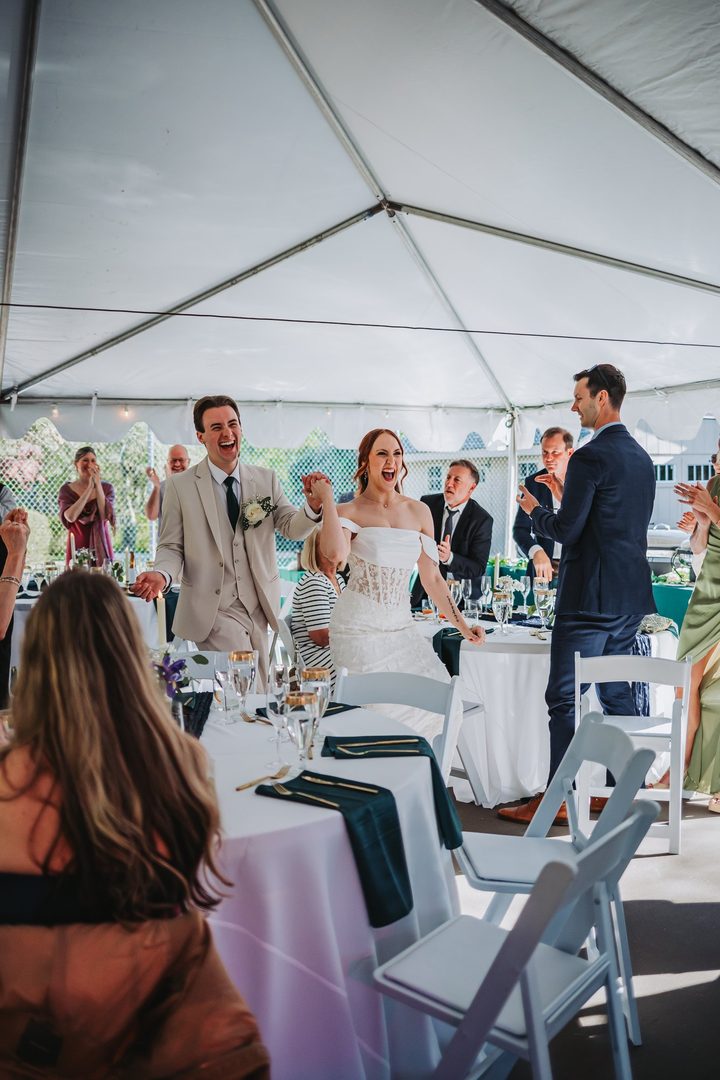 Brooke and Max welcomed into the reception with raised glasses