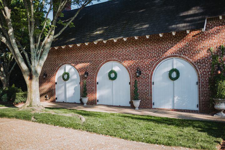 The brick Carriage House and its white arched doors in spring sunshine