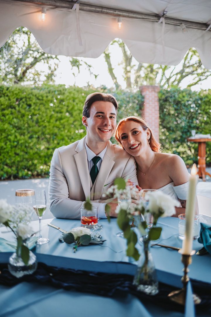 Brooke and Max smiling together at their reception table