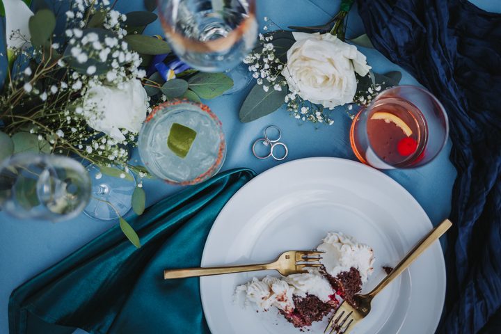 Wedding cake, drinks, and flowers on a green reception table