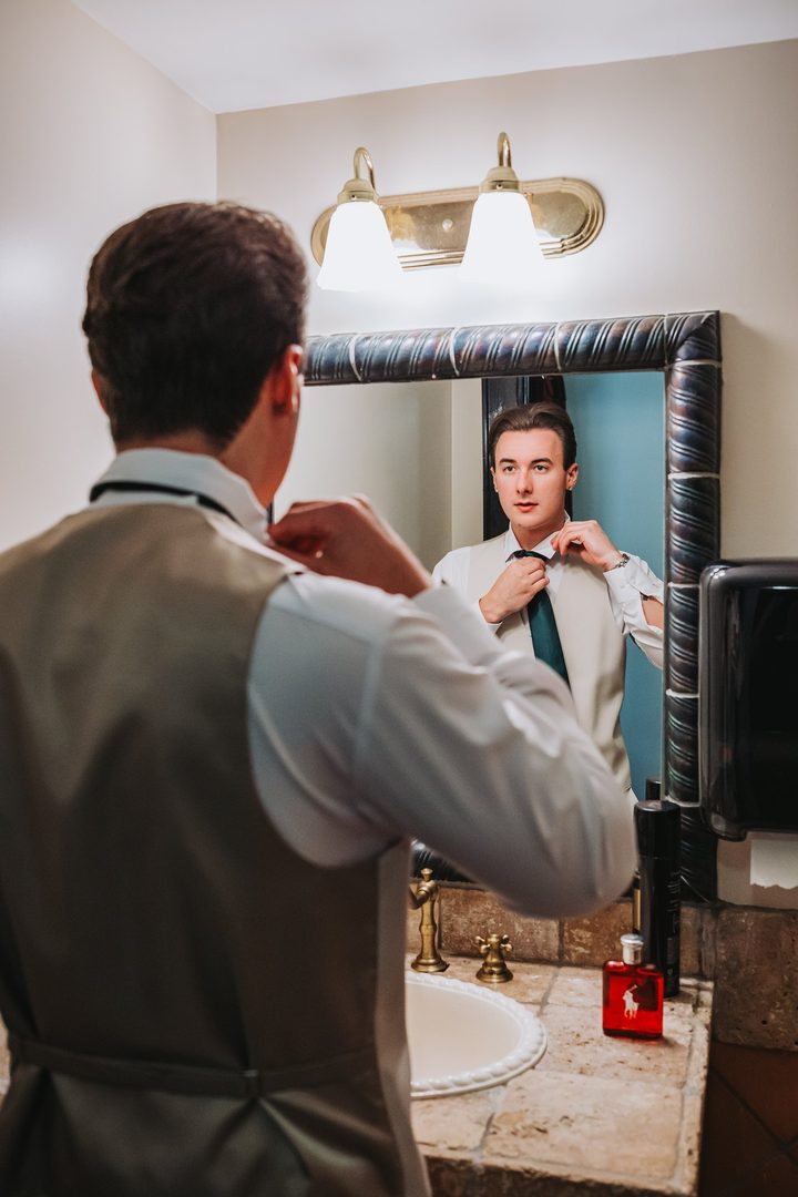 Max adjusting his tie in the mirror before the ceremony