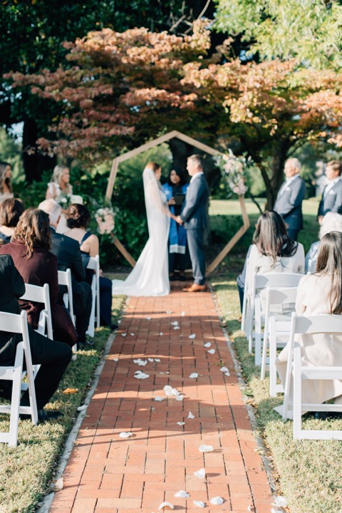 The couple exchanging vows beneath the autumn leaves