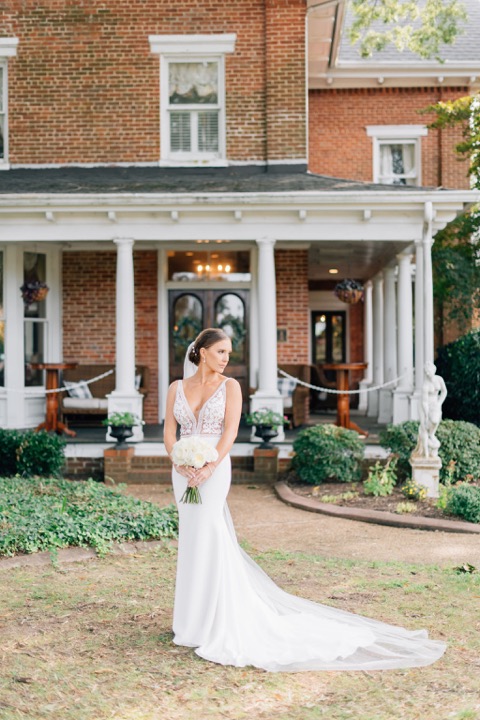 Sarah holding her bouquet in front of the Manor