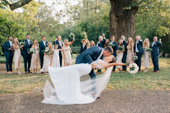 The newlyweds sharing a celebratory dip in front of their wedding party