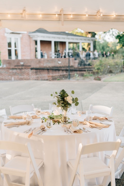 A reception table set with white linens and flowers