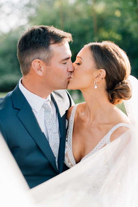 A close portrait of the newlyweds sharing a kiss