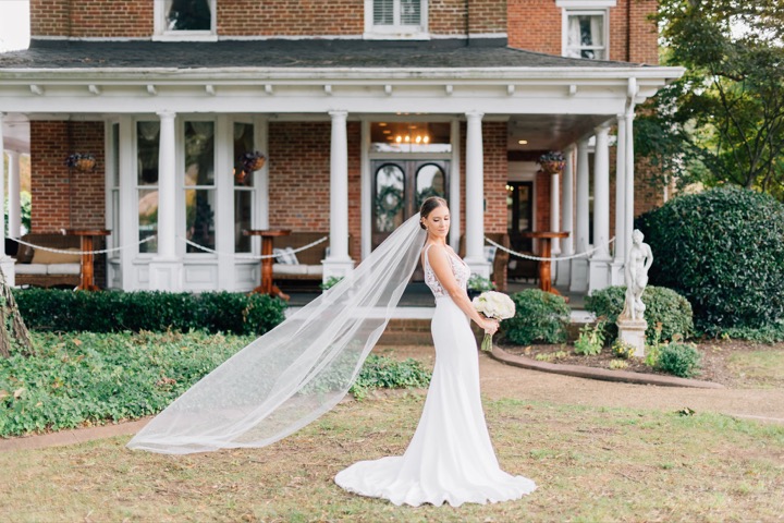 A bridal portrait with a flowing veil beside the Manor