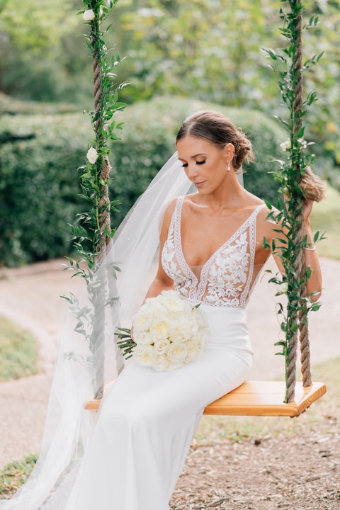 Sarah looking down at her bouquet on the garden swing