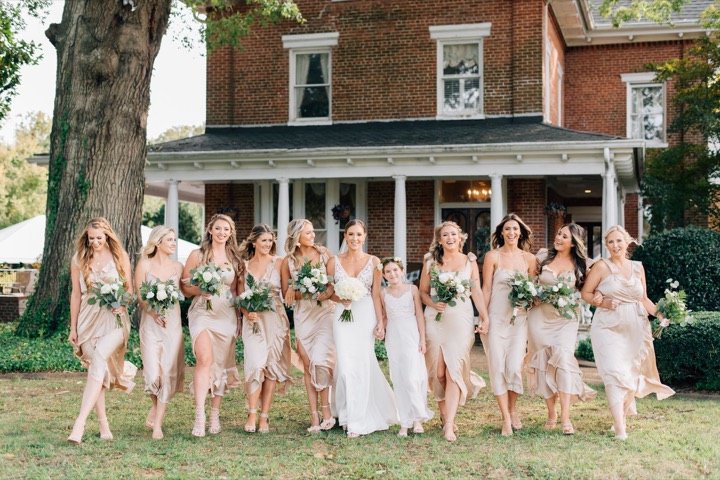 The bridal party raising their bouquets on the lawn
