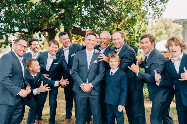 The groom posing with his wedding party beneath the trees