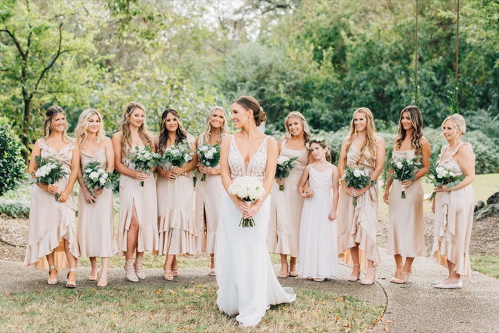 The bridal party posing with white bouquets