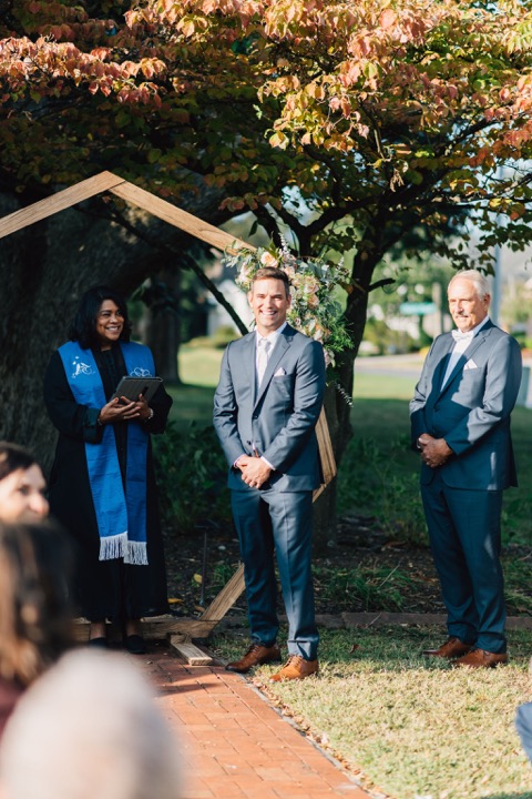 The groom waiting beneath the ceremony arbor