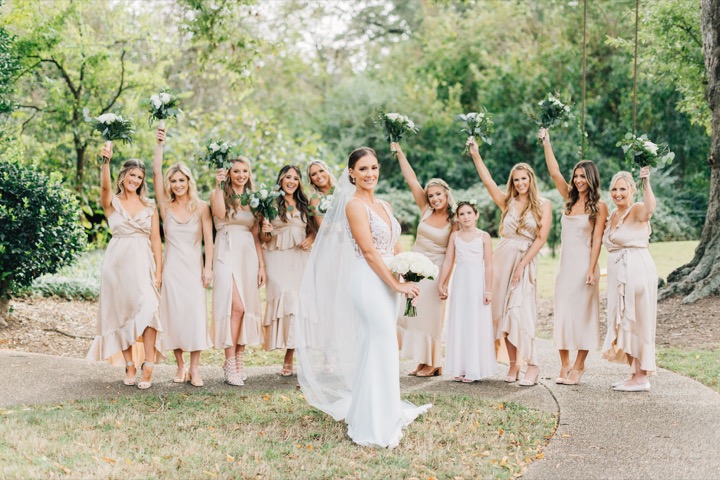 The bridal party walking through the garden with their bouquets raised