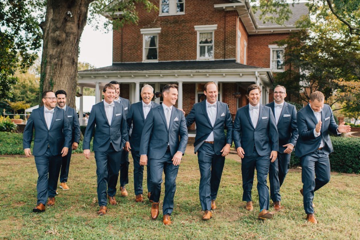 The groom and his wedding party walking across the lawn