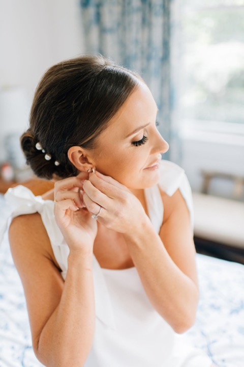 Sarah putting on her earrings beside the cottage window