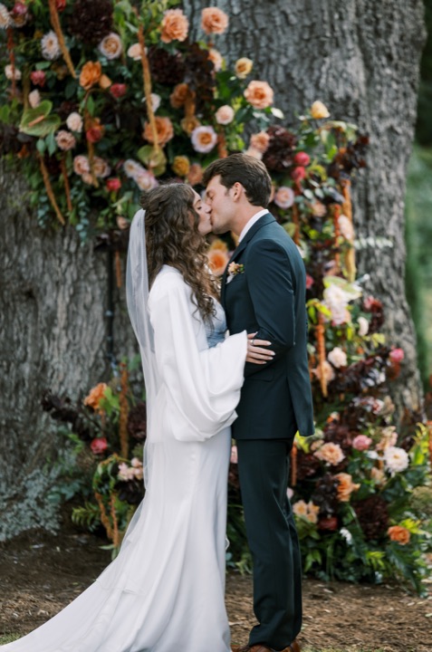 Madelynne and Parker kissing beside the autumn floral arrangement
