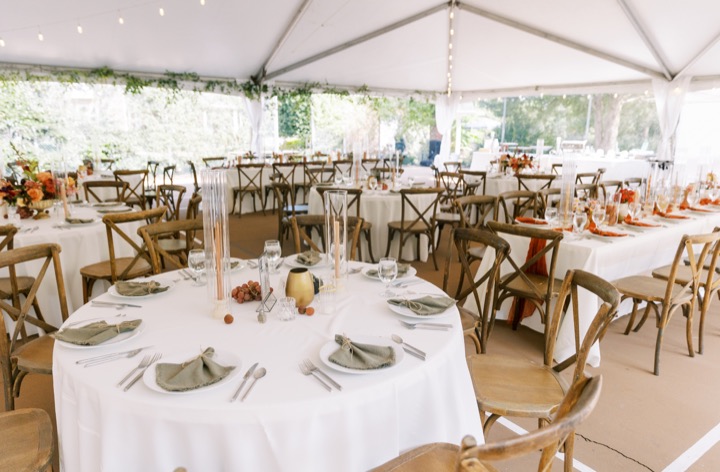 Reception tables set beneath the white tent with flowers and candles