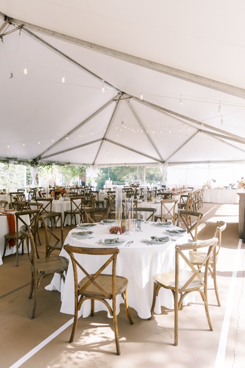 Wooden chairs and cream linens beneath the reception tent