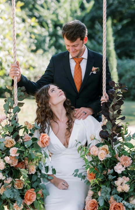 Parker leaning toward Madelynne on the flower-filled garden swing