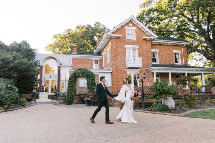 Madelynne and Parker walking hand in hand in front of the Manor