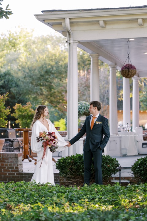 Madelynne and Parker holding hands beside the white-columned porch