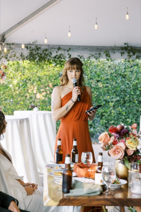 A guest giving a toast beside a colorful floral arrangement