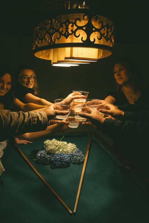 Friends raising their glasses around the Cellars table