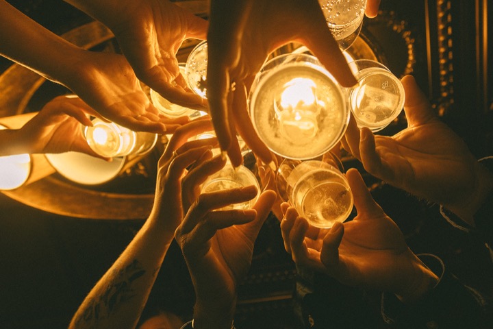 Glasses raised in a toast around a glowing lantern