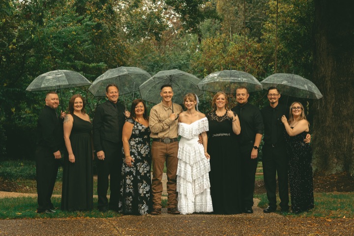 The wedding party gathered beneath umbrellas in the gardens