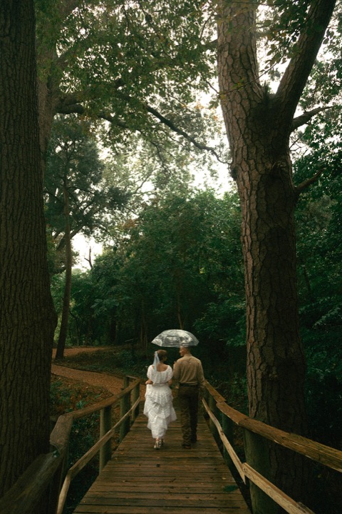 The newlyweds walking hand in hand across the wooden bridge