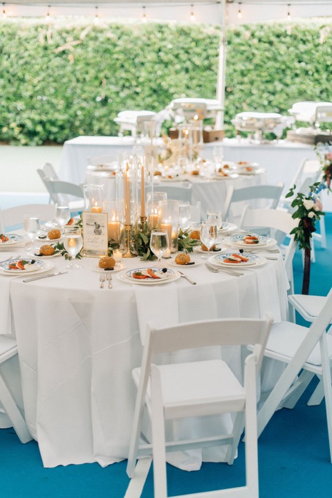 Reception tables set with white linens, flowers, and candles