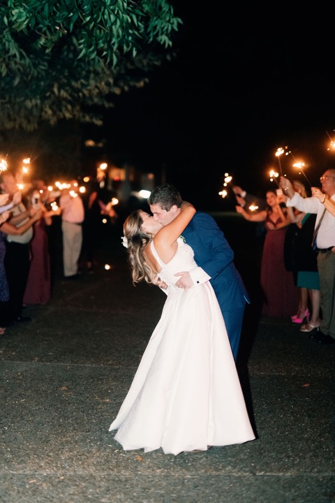The couple kissing as guests hold sparklers around them