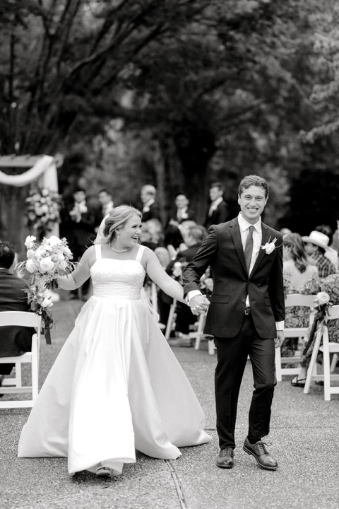 A black-and-white photograph of the couple walking up the aisle