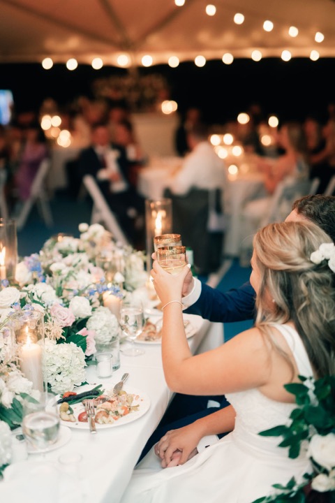 Guests raising a glass around a candlelit reception table