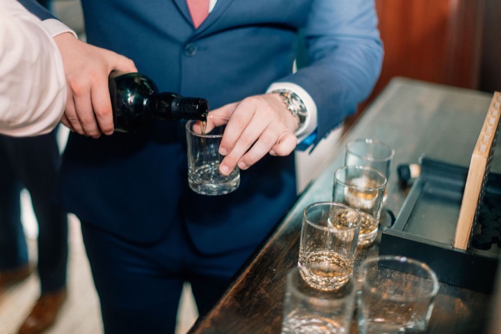 A drink being poured while the wedding party gets ready