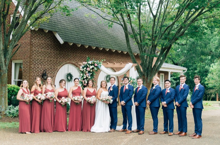 The wedding party lined up beside the floral arbor