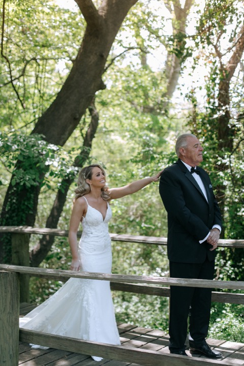Taylor and John reaching for each other on the wooden bridge