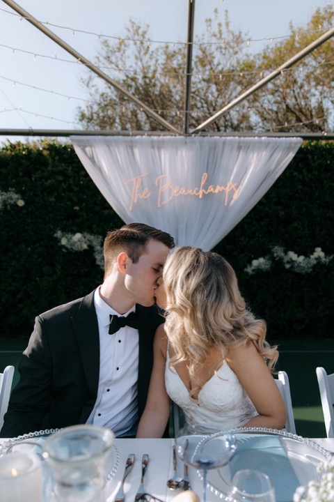 Taylor and John sharing a kiss at their reception table