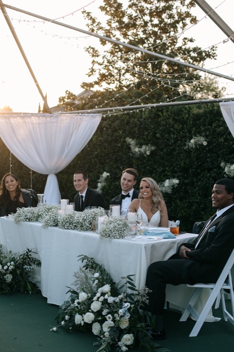 The wedding party dining beneath white drapery and string lights