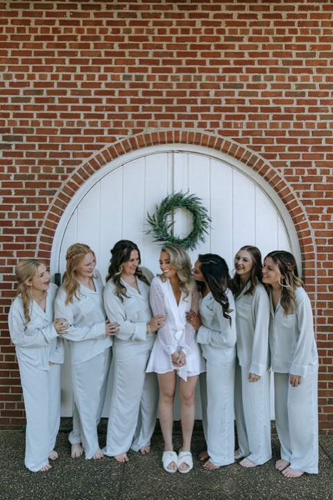 The bridal party posing by the white Carriage House doors
