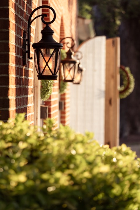 A glowing lantern beside the Carriage House doorway