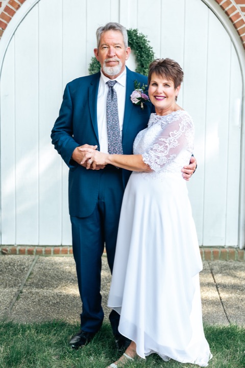 Dave and Leslie embracing in front of the white arched doors