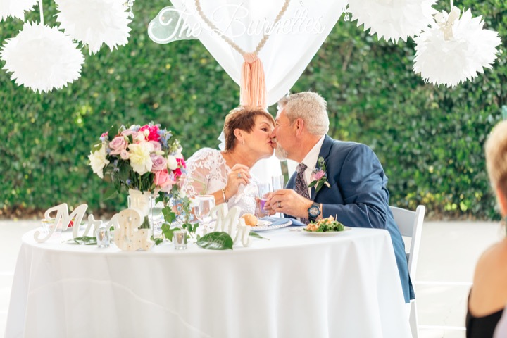 Dave and Leslie kissing at their flower-filled reception table